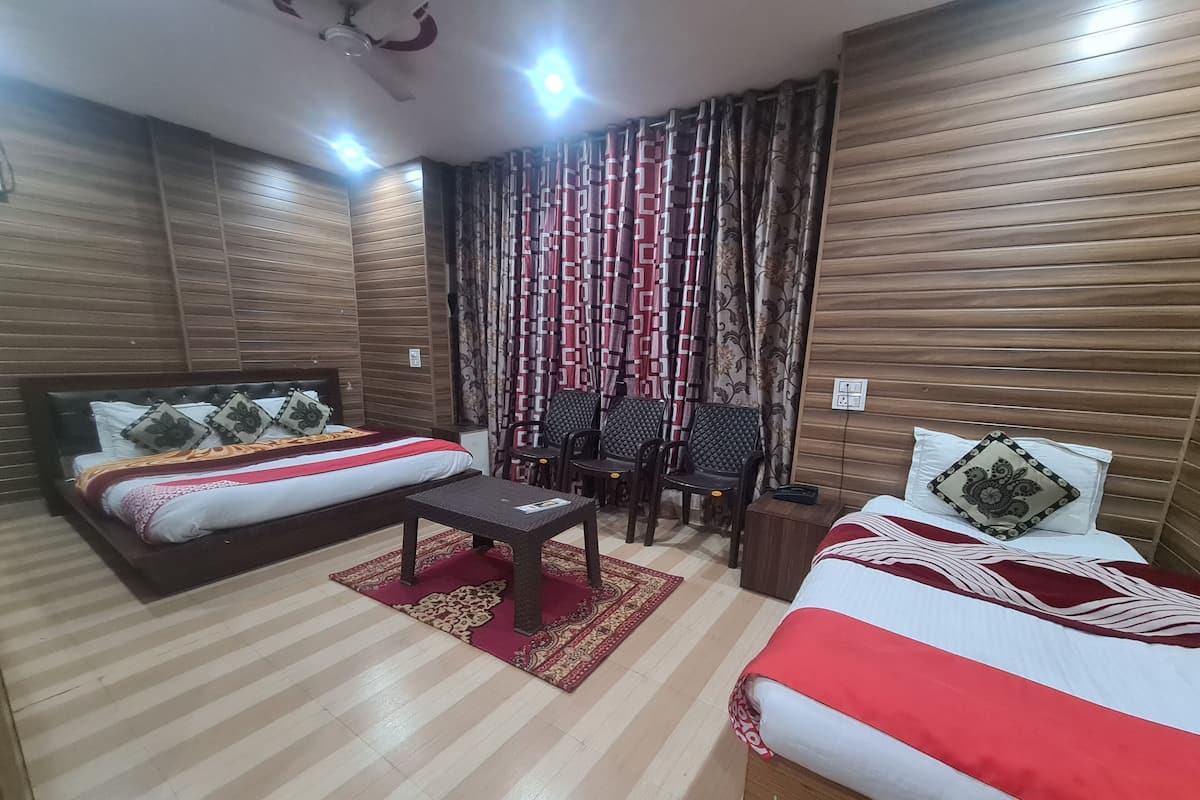 A hotel room with two beds, a small table, and a seating area with chairs.