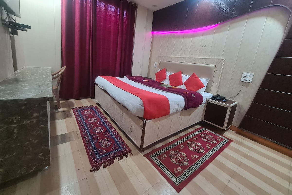 A bedroom with a bed, a nightstand, a chair, and two rugs.