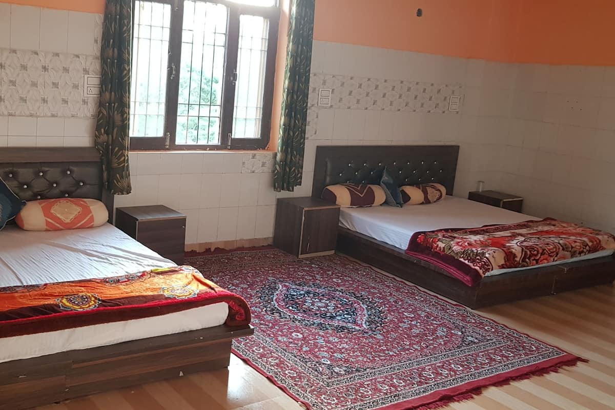 A hotel room with two beds, a large window with curtains, patterned wall tiles, and a red and blue patterned rug.