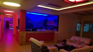 Zona de recepción con mostrador, cartel de recepción y pantalla de televisión.
