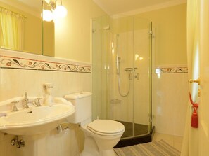 Une salle de bain équipée d’un lavabo, de toilettes et d’une douche à parois de verre.