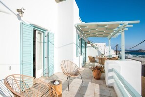 A balcony with wicker chairs, a table, and a potted plant.