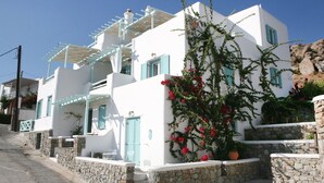 Un edificio blanco con contraventanas azules y una escalera de piedra.