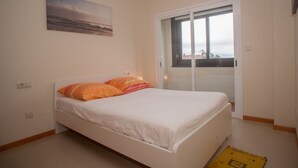 A bedroom with a bed, a window, and a door.