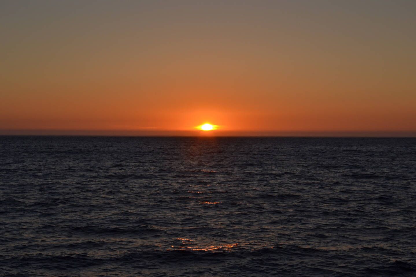 Un atardecer sobre un mar tranquilo.