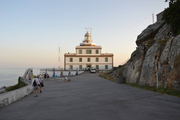 Un bâtiment situé sur la côte, doté d’une tour imposante, d’une promenade dallée et d’une falaise rocheuse.