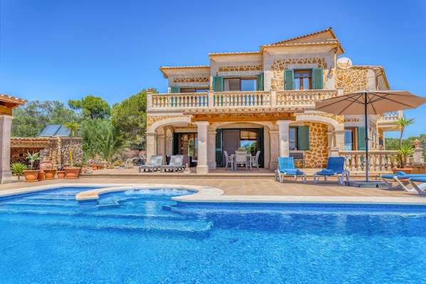 A two-story house with a swimming pool, outdoor seating, and a patio area.