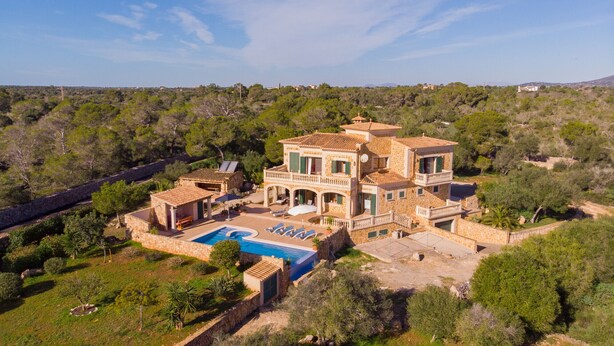Une grande villa dotée d’une piscine, de nombreux balcons et d’une façade en pierre.