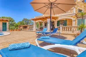 A poolside area with lounge chairs and an umbrella.