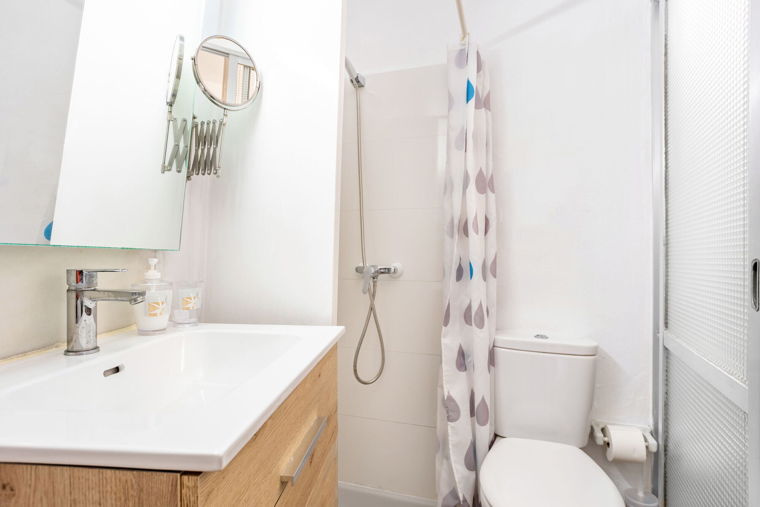 A bathroom with a white sink, mirror, and shower curtain.