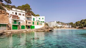 A coastal building with a clear view of the sea, a rocky shoreline, and a sandy beach in the background.