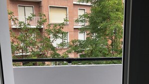 Un balcon donnant sur un immeuble en briques, doté de nombreuses fenêtres et de plusieurs balcons.