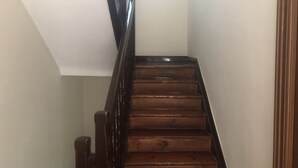 Un escalier en bois avec une main courante sombre menant à un palier.