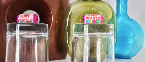 Tres recipientes de vidrio con etiqueta 'Love Hearts', colocados frente a una botella de cobre y otra verde.