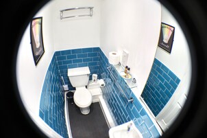 Un baño con inodoro, lavamanos y paredes de azulejos azules.