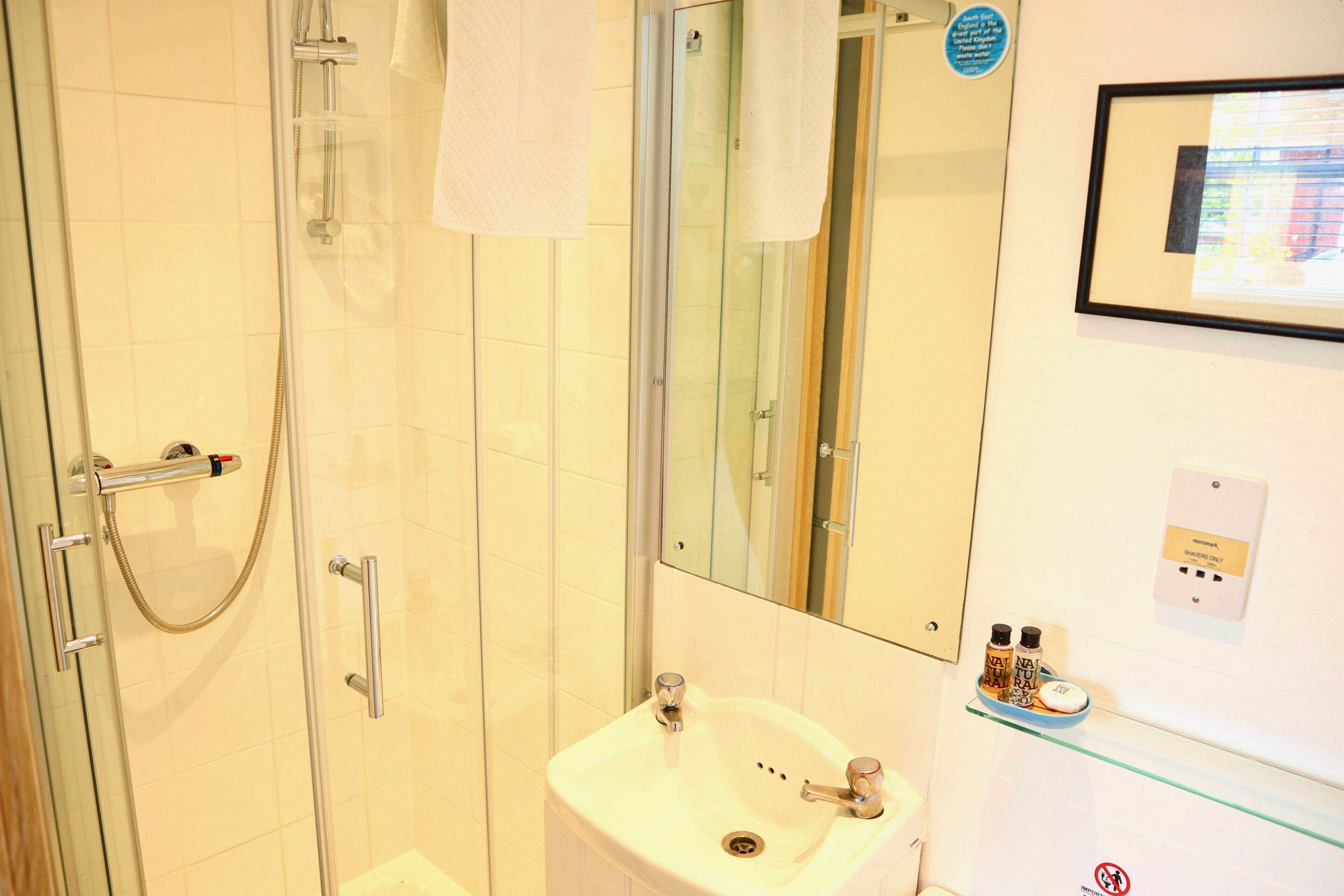 Un bagno con box doccia in vetro, lavandino e specchio.