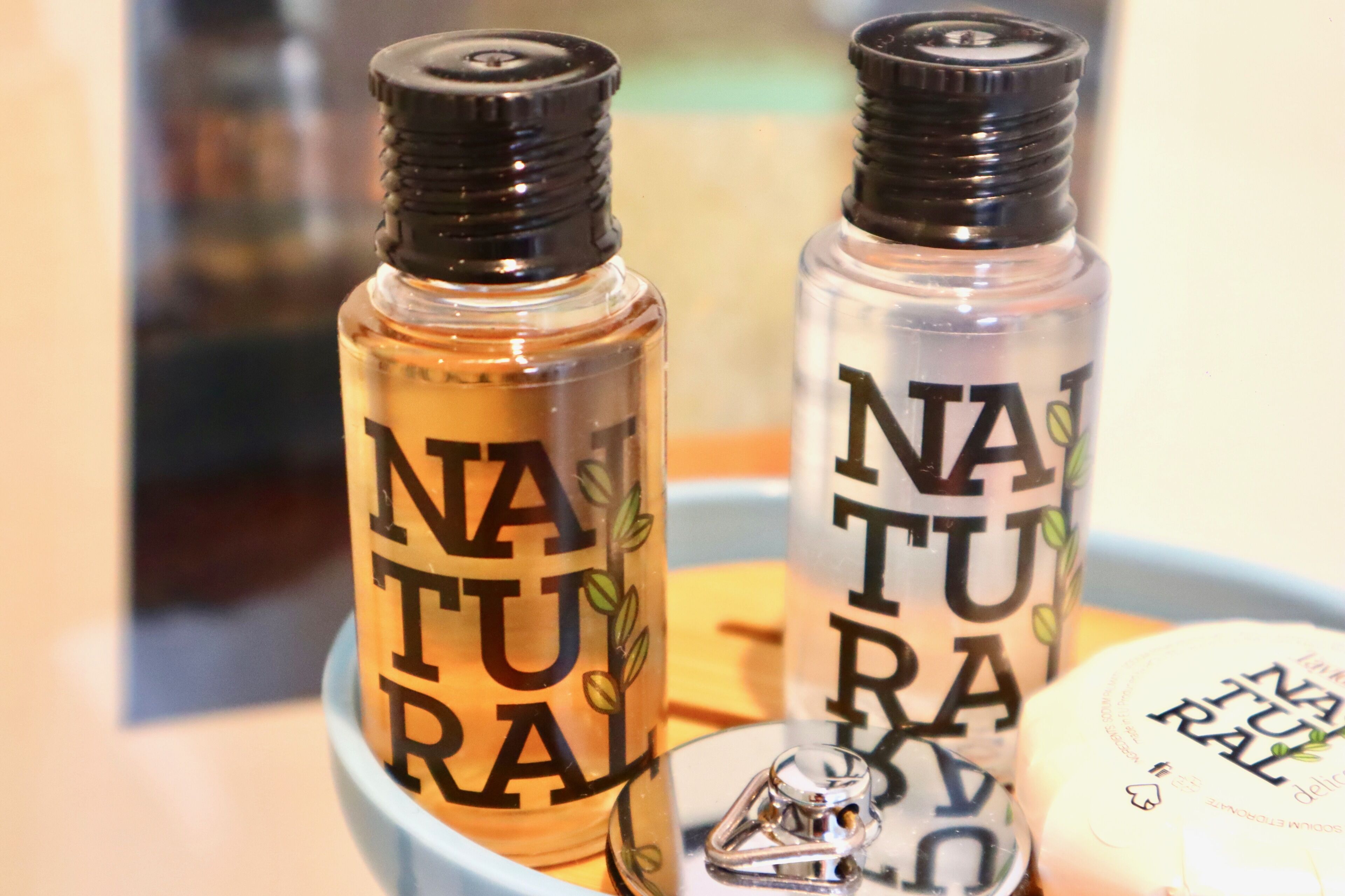Dos botellas con la etiqueta 'NATURAL' y un diseño de planta, junto con una botella pequeña con etiqueta similar.