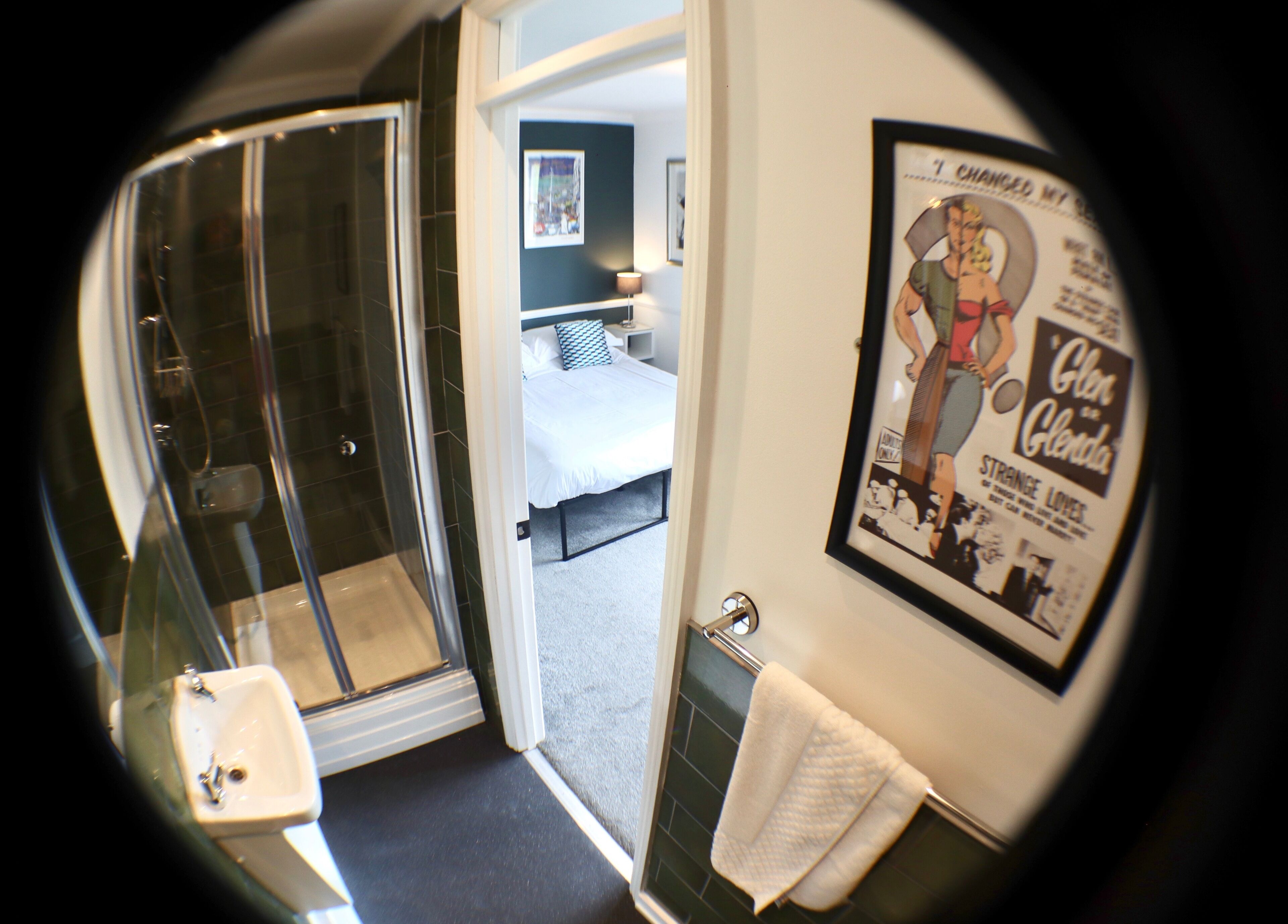 A bathroom with a glass shower enclosure, a sink, and a towel hanging on the wall.