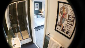 A bathroom with a glass shower enclosure, a sink, and a towel hanging on the wall.