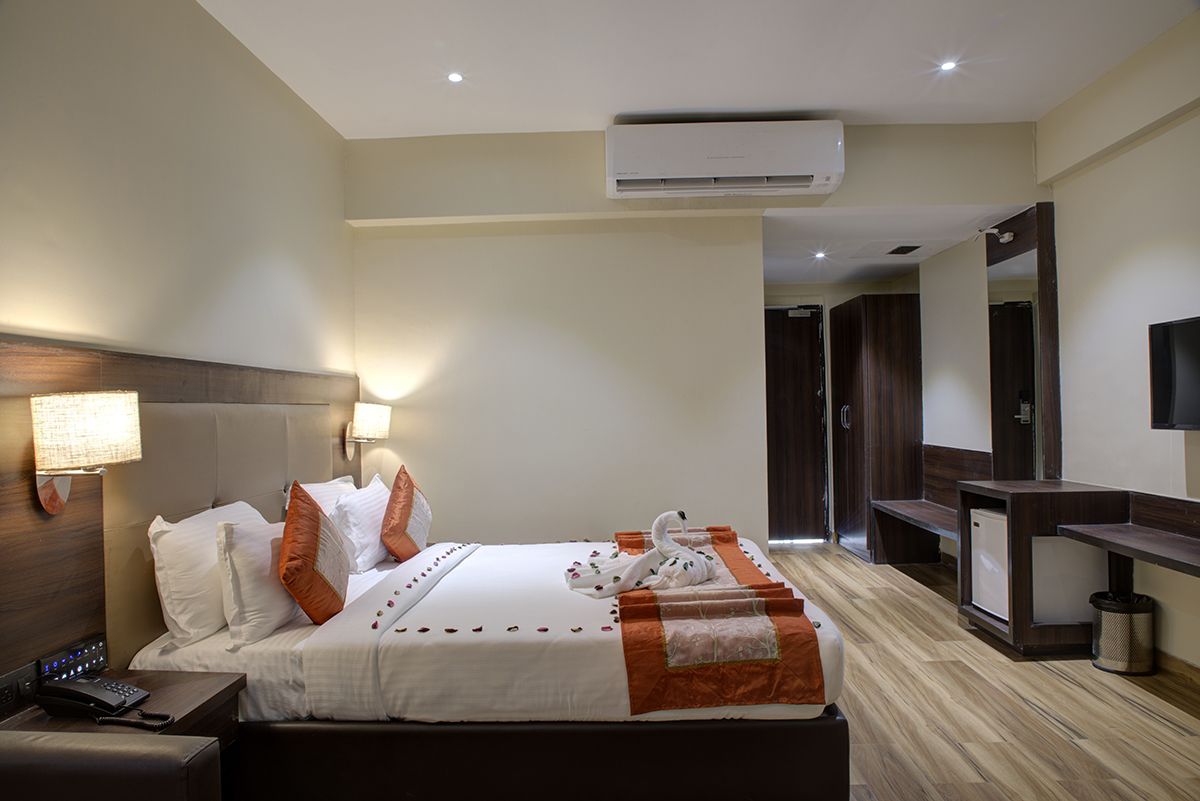 Ein Hotelzimmer mit Bett, Nachttisch, Lampe, Klimaanlage und Fernseher.