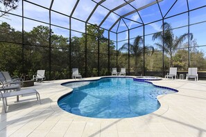 An indoor swimming pool with clear blue water, surrounded by white tiled flooring and white lounge chairs.