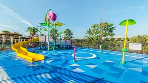 A water park with a yellow slide, a water fountain, and a blue patterned floor.