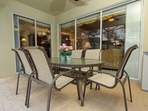A round table with four chairs, a vase with pink flowers, and a view through large glass doors. - Ov3776 - Windsor Hills Resort - 5 Bed 5 Baths Villa (Kissimmee)