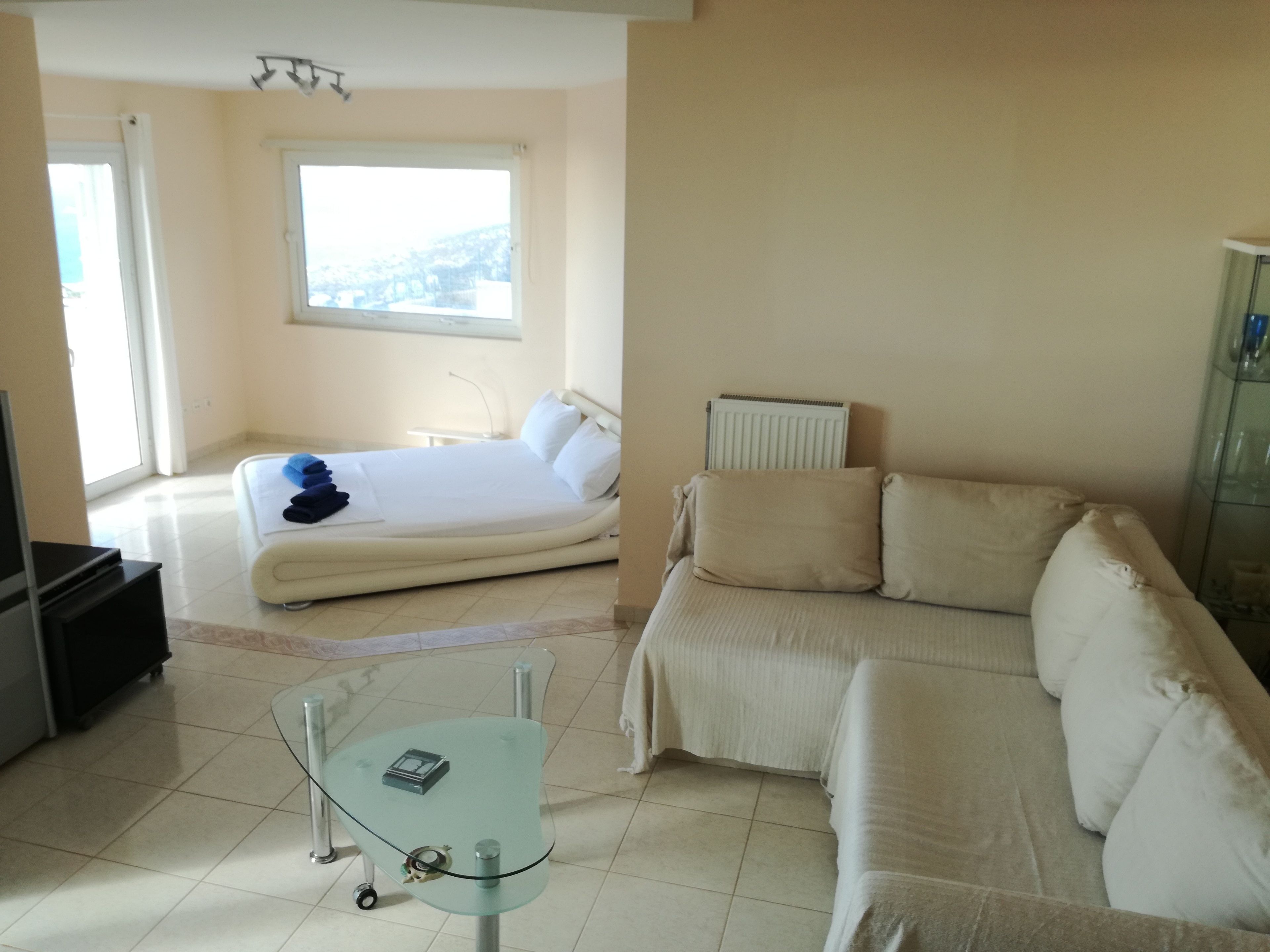 Une chambre d’hôtel avec un lit, un canapé, une table en verre et un radiateur.