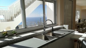 Een moderne keuken met een groot raam, een roestvrijstalen spoelbak en een betegelde achterwand.