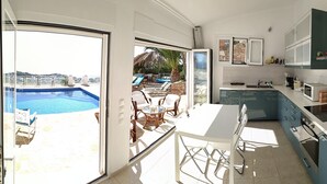 Een moderne keuken met uitzicht op een zwembad en een terras.