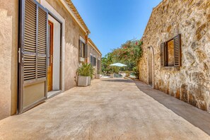A narrow alleyway with stone walls, a door, and a window with shutters.