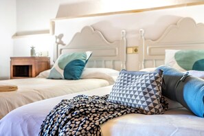 A neatly made bed with patterned pillows and a blanket, a wooden nightstand with a lamp, and a white headboard.
