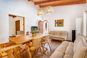 A dining area with a wooden table and chairs, a sofa, and a colorful abstract painting on the wall.