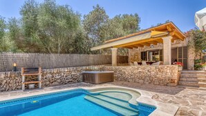Une piscine avec un mur en pierre et une pergola dotée d’un espace salon extérieur.