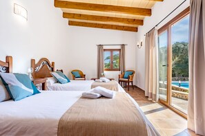 A hotel room with two beds, a window with curtains, a view of a pool, and a wooden ceiling.