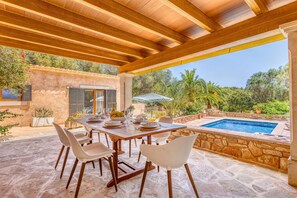 An outdoor dining area with a pool and a view of the surrounding greenery.