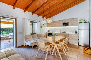 A modern kitchen with wooden cabinets, a dining area with a table and chairs, and a built-in oven.
