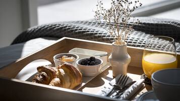 Aamiaistarjotin, jossa on croissantteja, marjoja ja lasi appelsiinimehua puupöydällä.