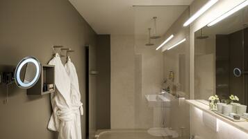 A modern bathroom with a glass-enclosed shower, a vanity with a mirror, and a robe hanging on a rack.