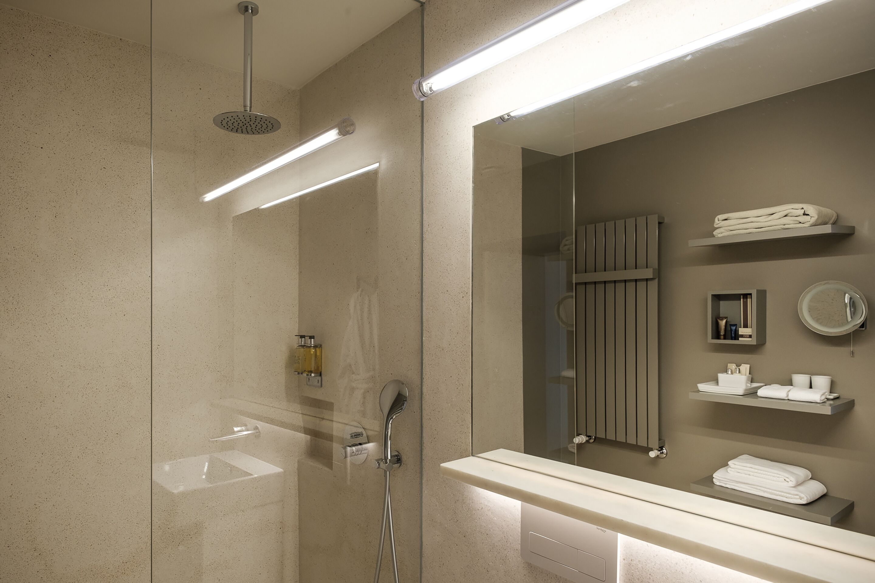 Une salle de bain moderne avec une douche à parois de verre, un lavabo, un miroir et un porte-serviettes.