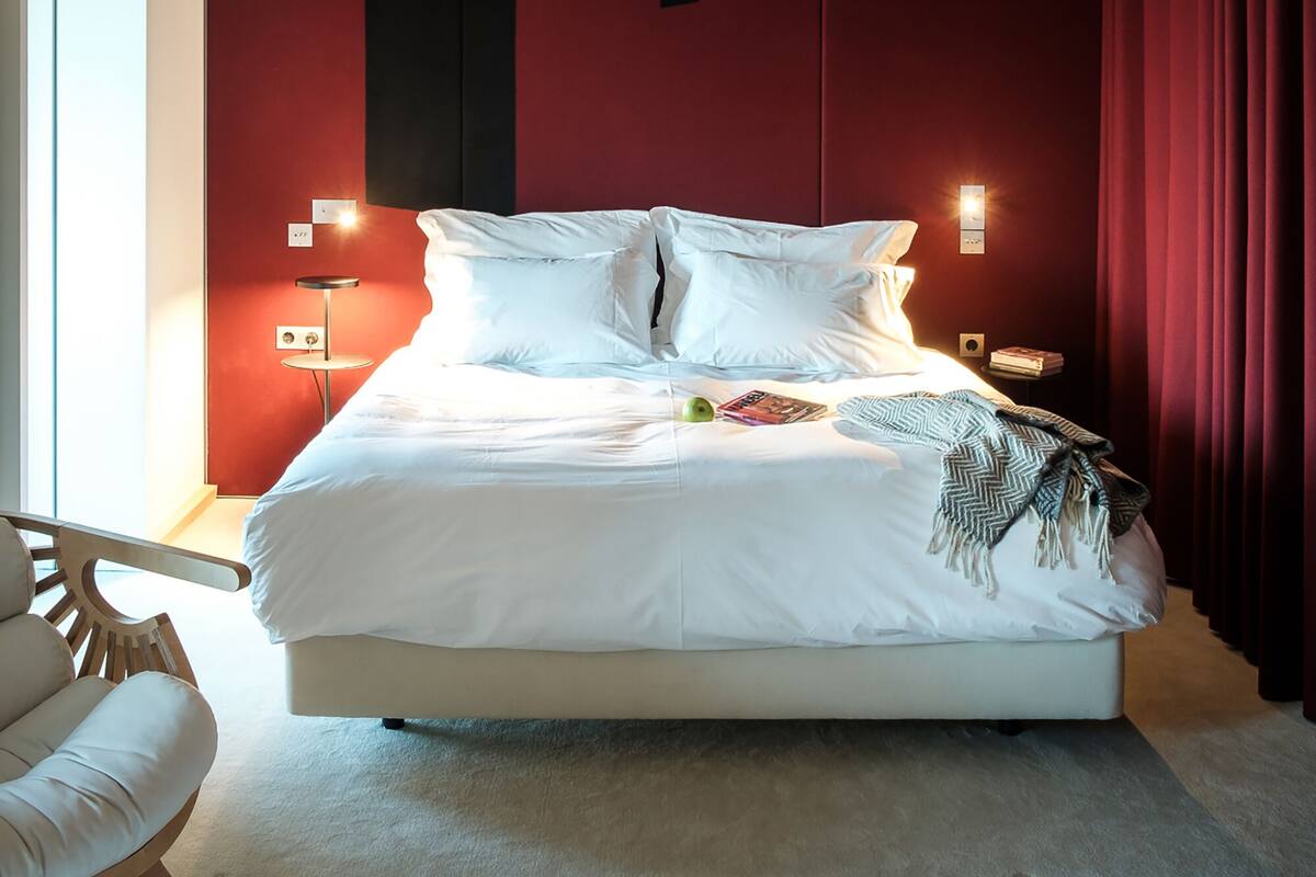 A bedroom with a large bed, red walls, and a sloped ceiling.