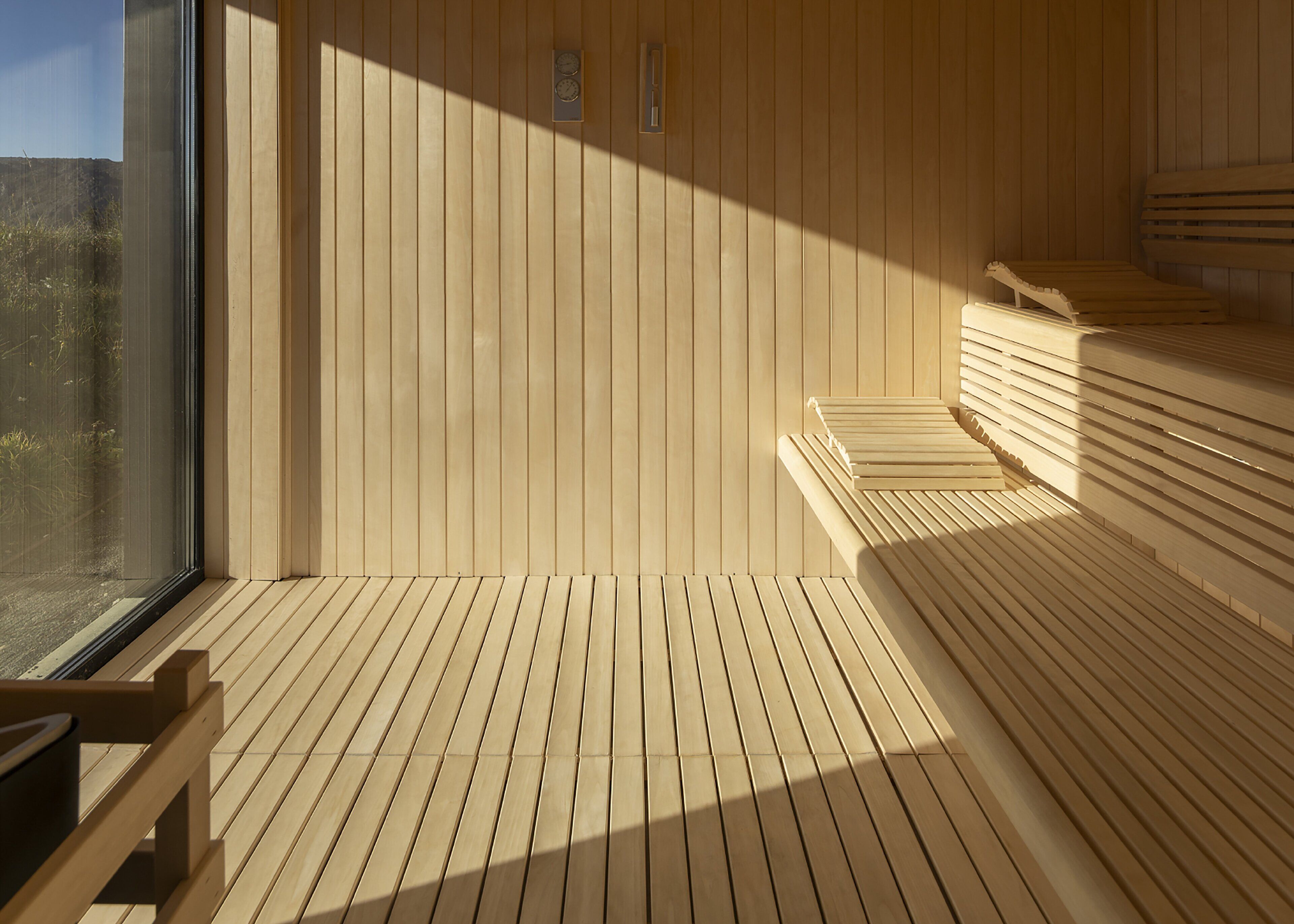Uma sauna de madeira com bancos e uma janela grande.