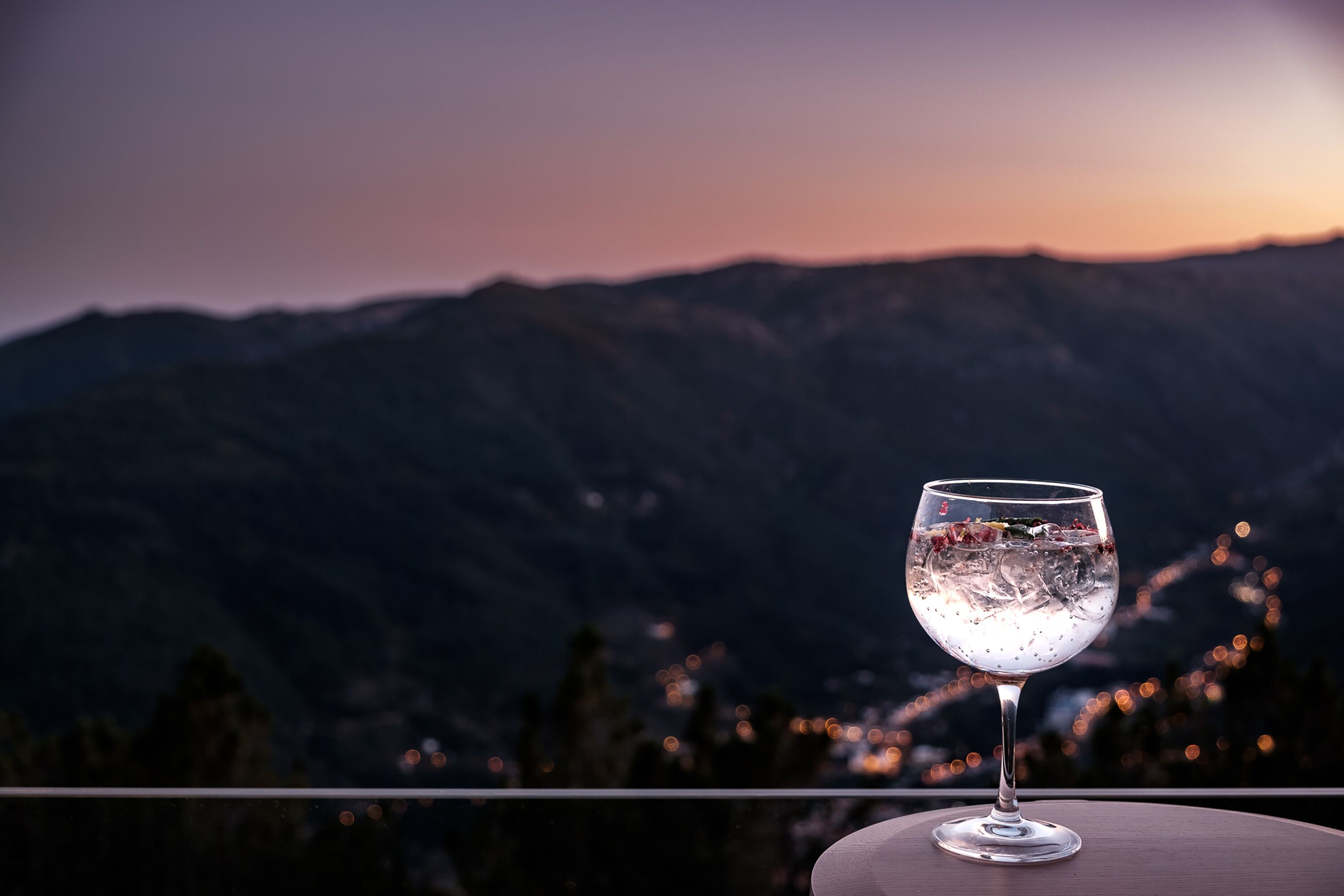 Een glas water op een tafel, met een bergzicht op de achtergrond.