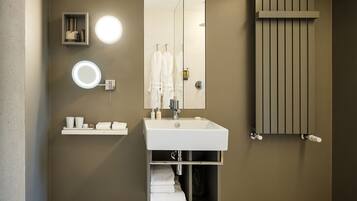 A modern bathroom with a large mirror, a round light, a towel rack, and a built-in heater.