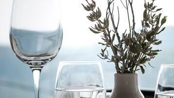 A table set with a wine glass, a water glass, a vase with greenery, and cutlery.