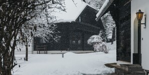 Un edificio cubierto de nieve con un banco y un farol.