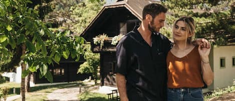 A couple standing in a garden with a rustic building in the background.