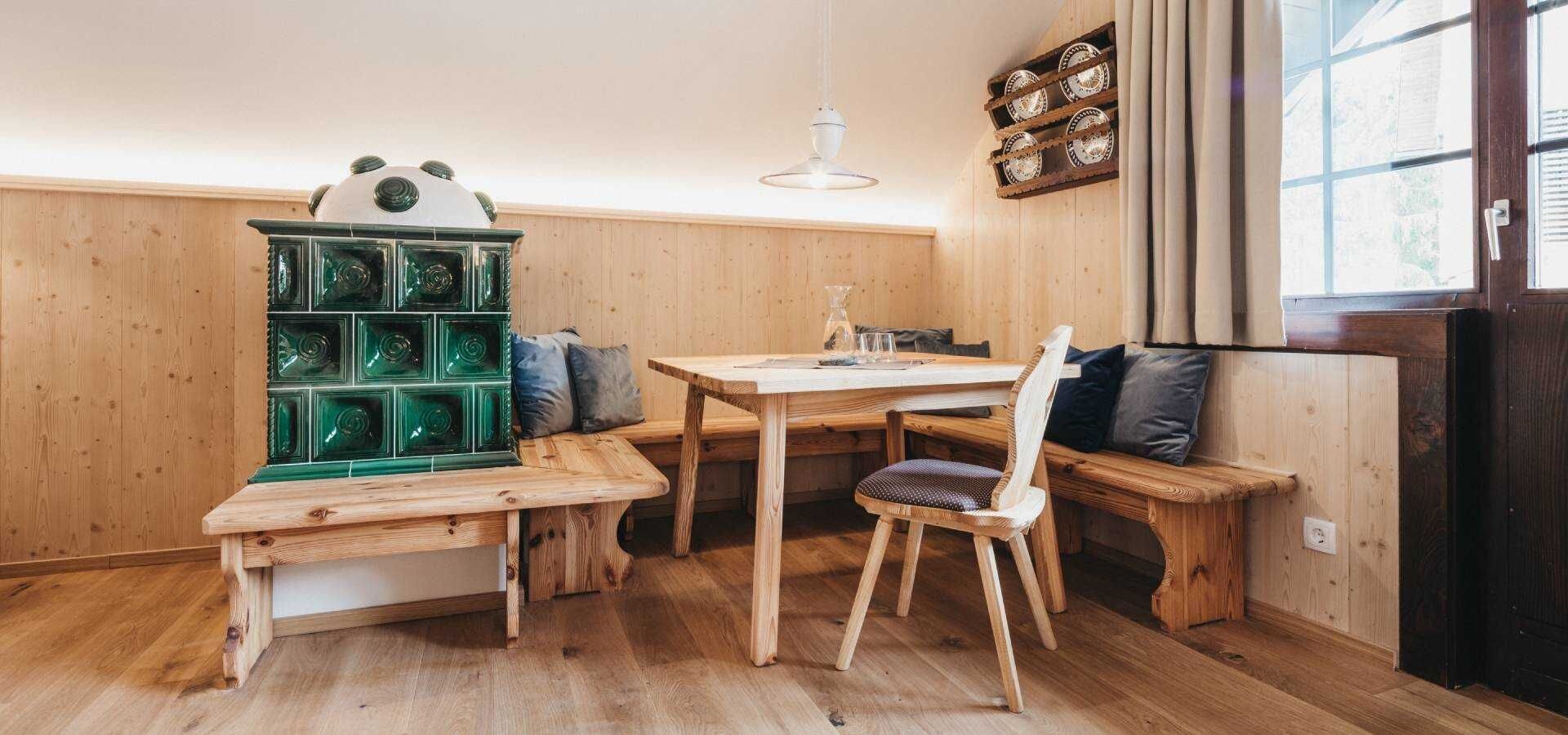 Un interno in legno con un tavolo da pranzo, panche e un armadietto verde.