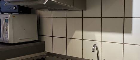 A modern kitchen with white cabinets, a stainless steel sink, and a built-in microwave.
