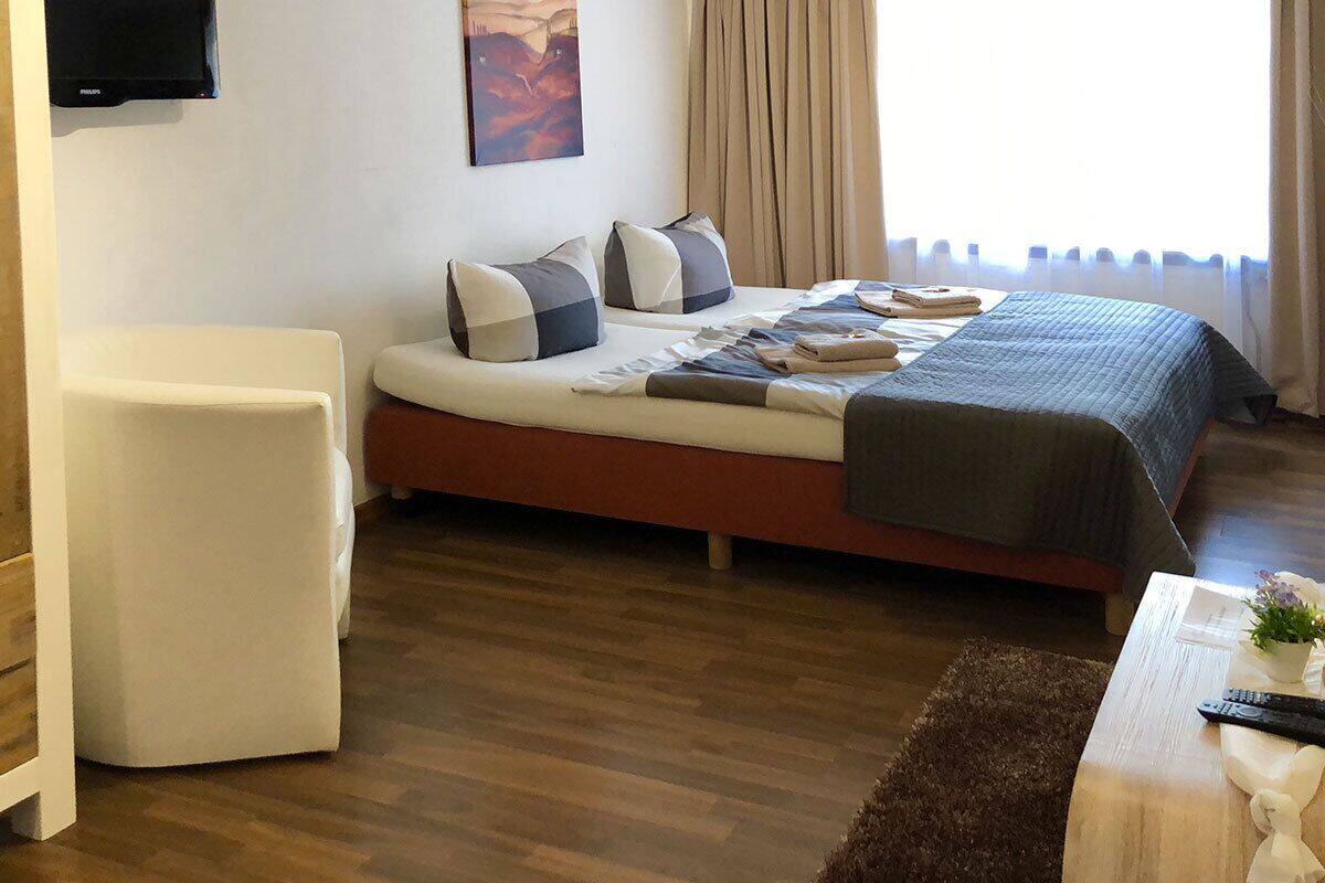Quarto com cama, uma cadeira, televisão de tela plana e um quadro na parede.